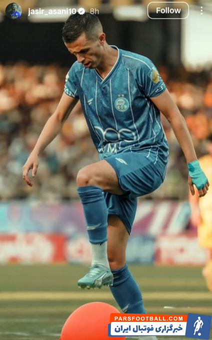 یاسر آسانی با پیراهن استقلال در حال ترکاندن یک بادکنک کاملاً قرمز است