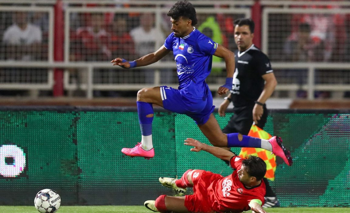 رامین رضاییان بازیکن استقلال در حال دریبل زدن شجاع خلیل زاده مدافع تراکتور