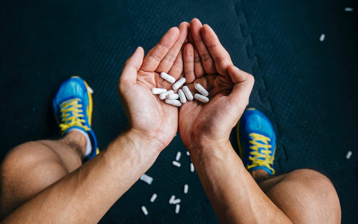 ورزشکاری نشسته با مشتی از قرص