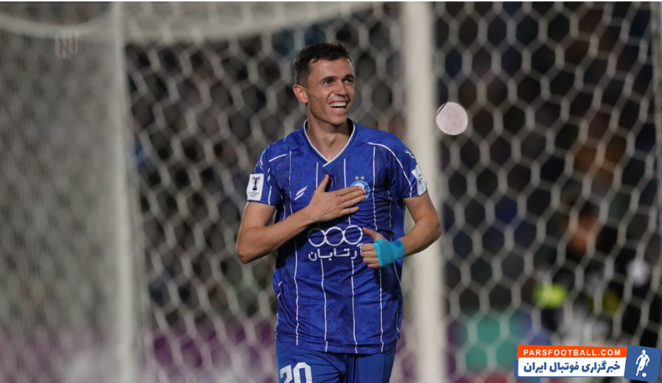 یاسر آسانی با پیراهن استقلال در حال ترکاندن یک بادکنک کاملاً قرمز است